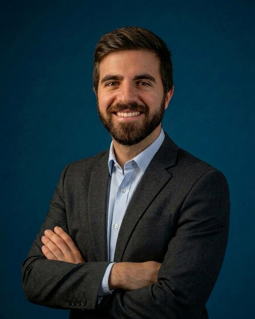 Ritratto di Claudio Ragusa, in giacca, su sfondo blu.